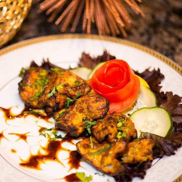 Narin's Bombay Brasserie's Indian chicken tikka with sauce, garnished with tomato, cucumber, and lettuce.