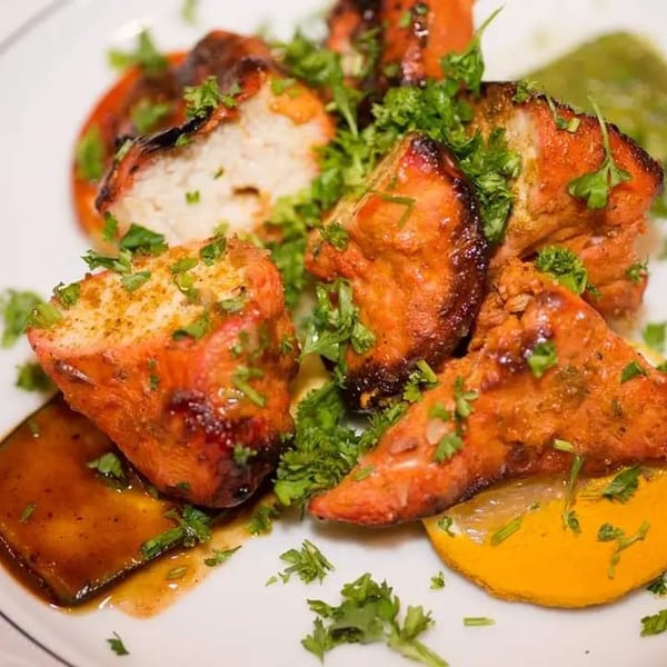 Close-up of Narin's Bombay Brasserie's Indian chicken tikka, garnished with fresh parsley and lemon.