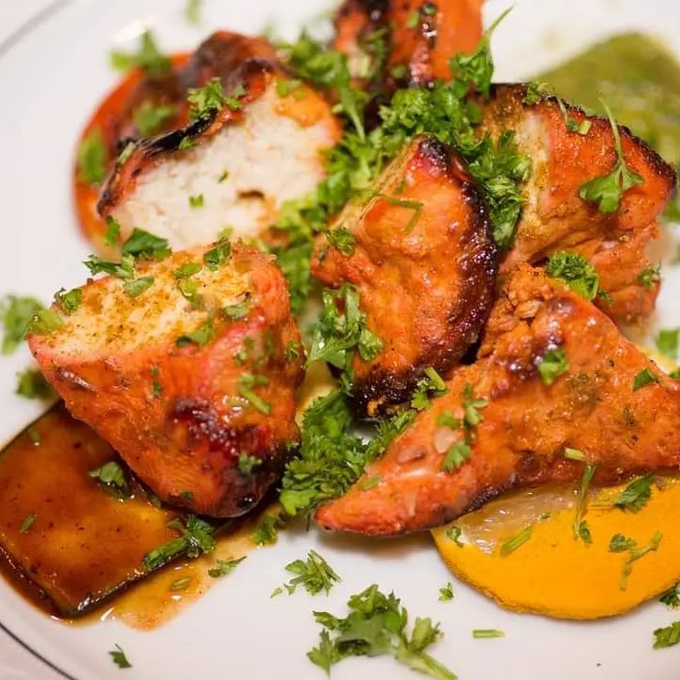 Close-up of Narin's Bombay Brasserie's Indian chicken tikka, garnished with fresh parsley and lemon.